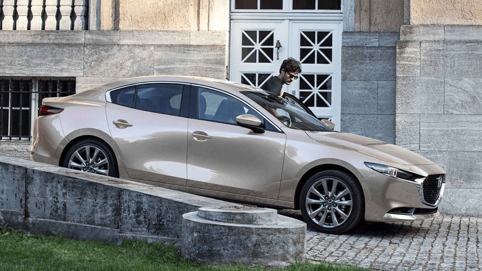 Vue latérale du Mazda3 2025 garé sur un pavé à l'extérieur.