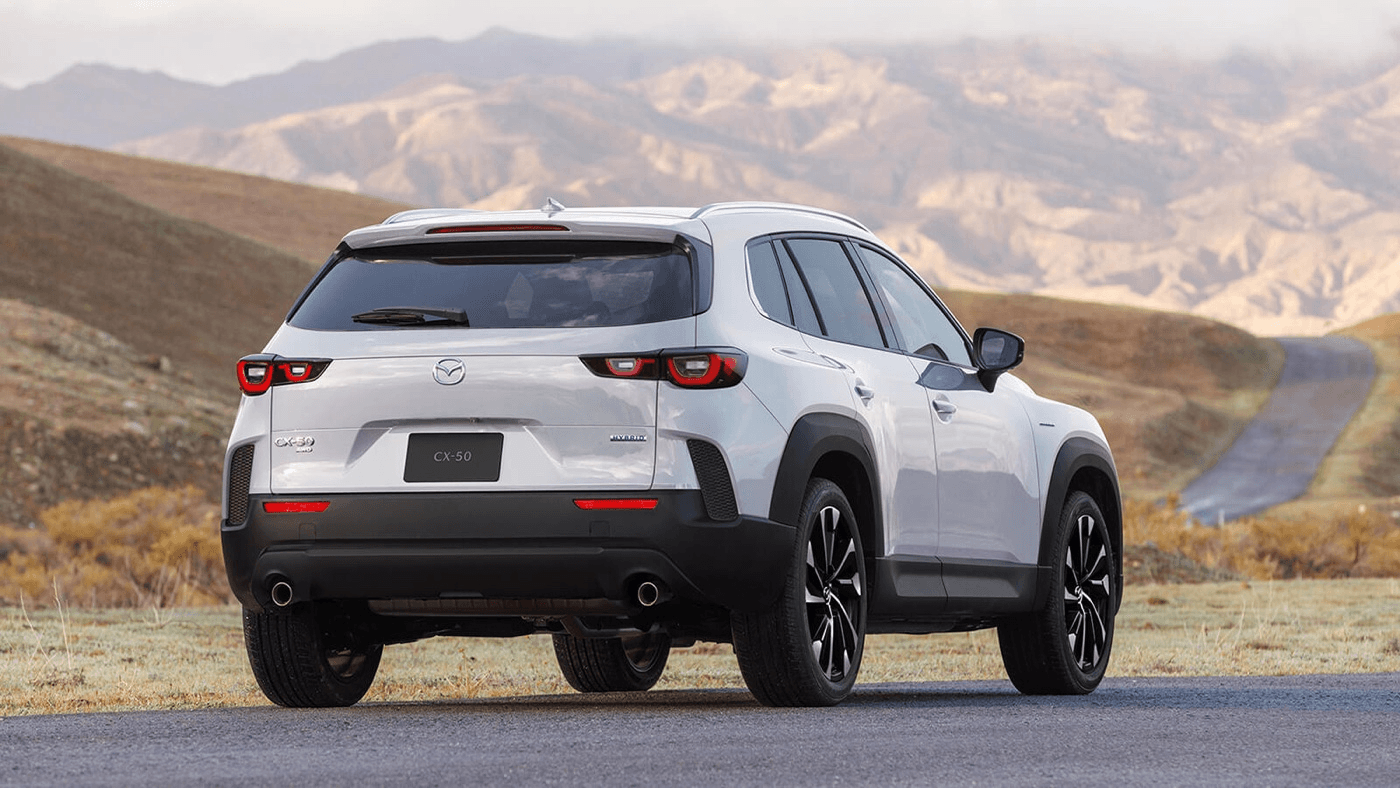 Vue 3/4 arrière du Mazda CX-50 hybride 2025 garé sur une route.