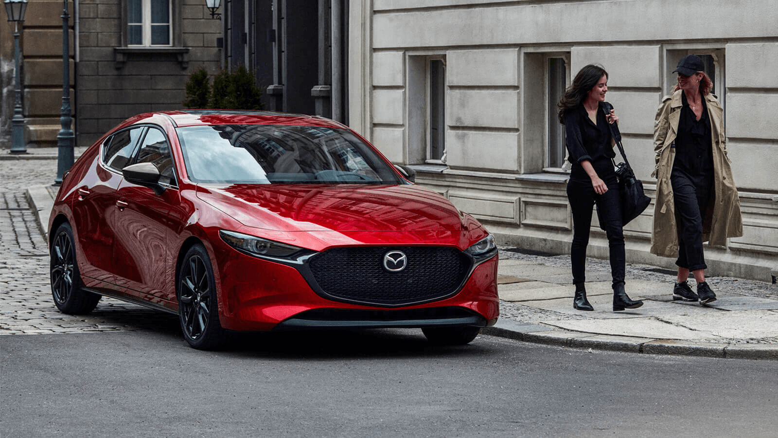 La Mazda 3 Sport stationné devant un bâtiment dans la rue.